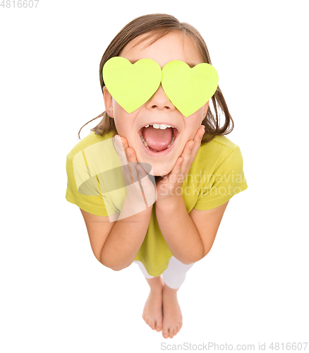 Image of Little girl is holding hearts over her eyes