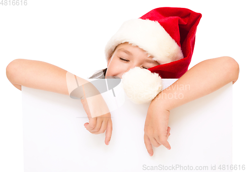 Image of Little girl in santa hat is holding blank board