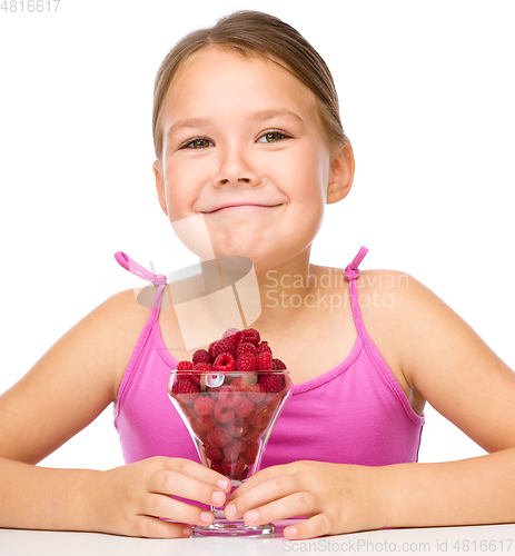Image of Happy little girl is eating raspberries