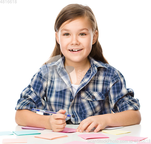 Image of Girl is writing on color stickers using pen