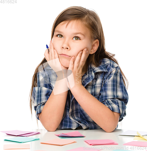 Image of Girl is writing on color stickers using pen