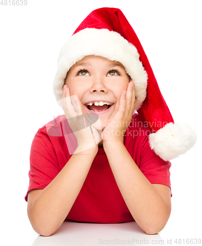Image of Little girl in santa hat is daydreaming