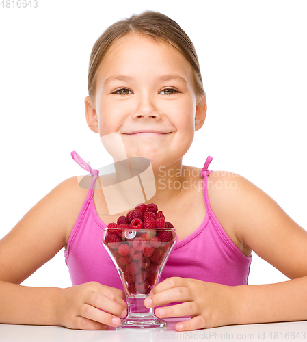 Image of Happy little girl is eating raspberries