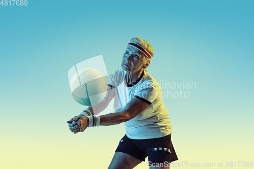 Image of Senior woman training in volleyball in sportwear on gradient background in neon light