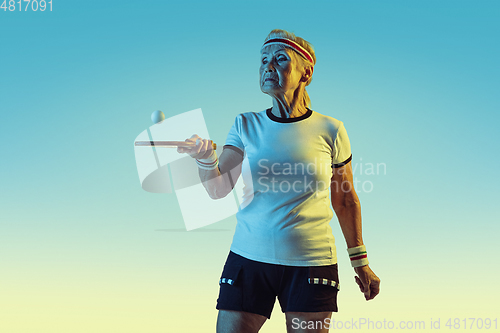 Image of Senior woman training in table tennis in sportwear on gradient background in neon light