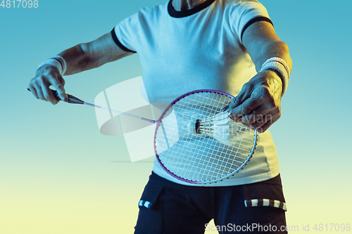 Image of Senior woman playing badminton in sportwear on gradient background in neon light