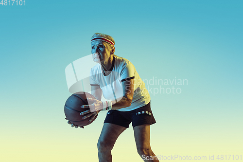 Image of Senior woman playing basketball in sportwear on gradient background in neon light