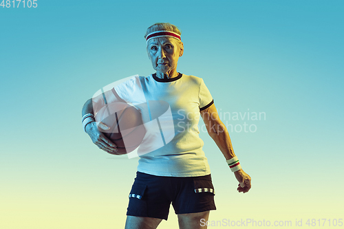 Image of Senior woman playing basketball in sportwear on gradient background in neon light