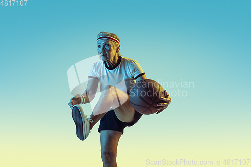 Image of Senior woman playing basketball in sportwear on gradient background in neon light