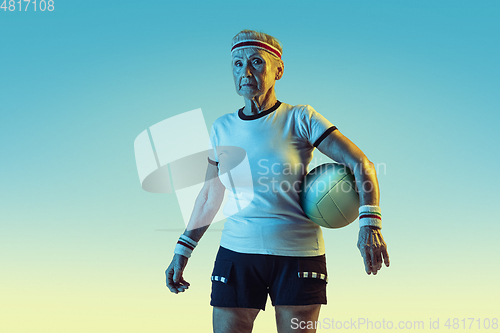 Image of Senior woman training in volleyball in sportwear on gradient background in neon light