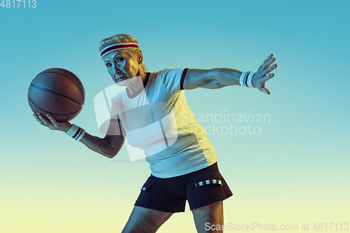 Image of Senior woman playing basketball in sportwear on gradient background in neon light