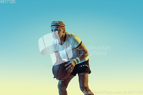 Image of Senior woman playing basketball in sportwear on gradient background in neon light