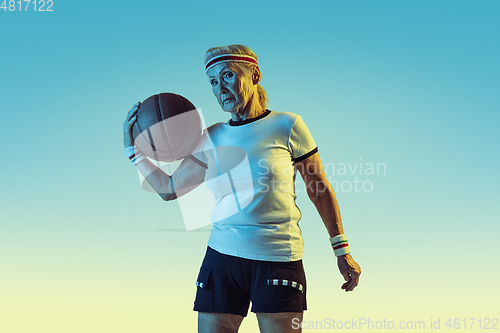 Image of Senior woman playing basketball in sportwear on gradient background in neon light