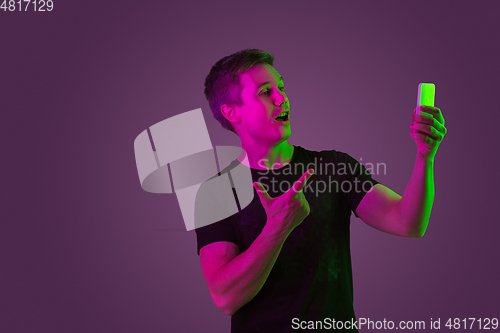 Image of Caucasian man\'s portrait isolated on purple studio background in neon light
