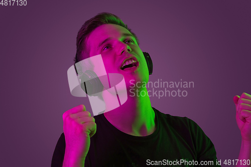 Image of Caucasian man\'s portrait isolated on purple studio background in neon light