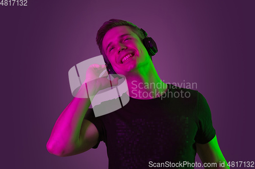 Image of Caucasian man\'s portrait isolated on purple studio background in neon light