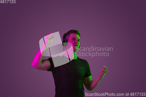 Image of Caucasian man\'s portrait isolated on purple studio background in neon light
