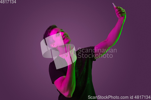 Image of Caucasian man\'s portrait isolated on purple studio background in neon light
