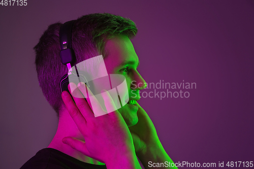 Image of Caucasian man\'s portrait isolated on purple studio background in neon light