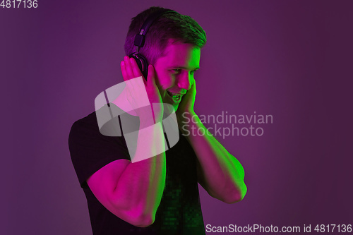 Image of Caucasian man\'s portrait isolated on purple studio background in neon light