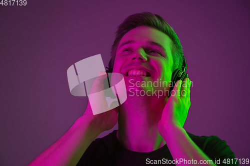Image of Caucasian man\'s portrait isolated on purple studio background in neon light