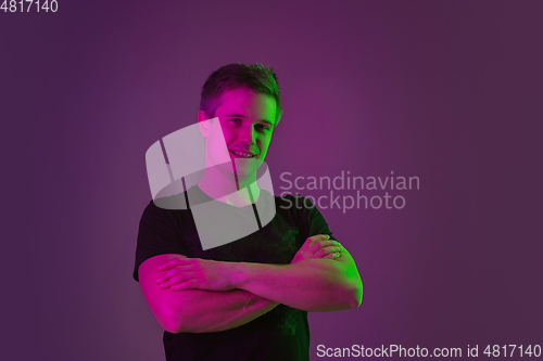 Image of Caucasian man\'s portrait isolated on purple studio background in neon light