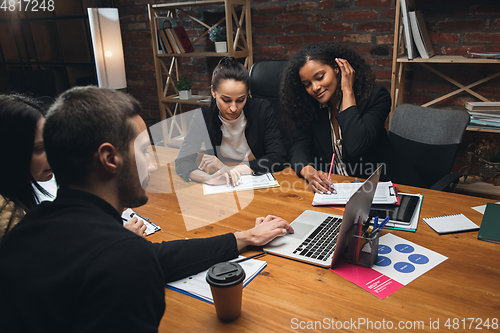 Image of Colleagues working together in modern office using devices and gadgets during creative meeting