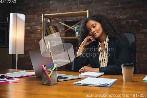 Image of Young woman working in modern office using devices and gadgets. Making reports, analitycs, routine processing tasks