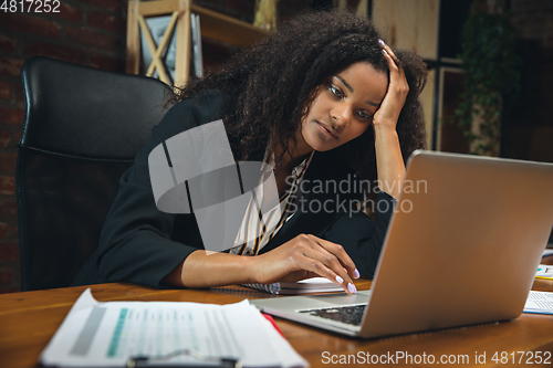 Image of Young woman working in modern office using devices and gadgets. Making reports, analitycs, routine processing tasks