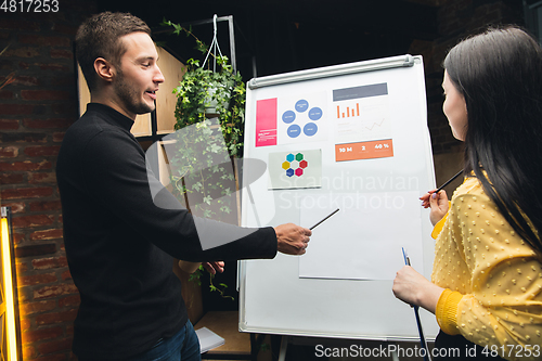 Image of Colleagues working together in modern office using flipchart during creative meeting