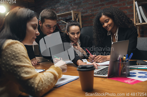 Image of Colleagues working together in modern office using devices and gadgets during creative meeting