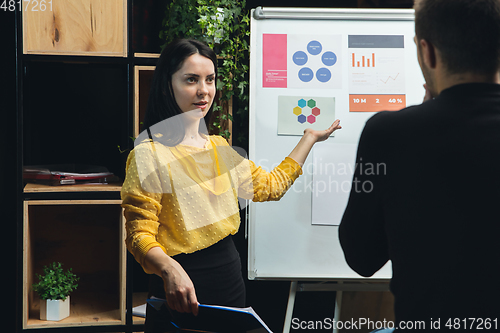 Image of Colleagues working together in modern office using flipchart during creative meeting