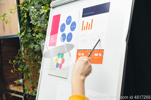 Image of Close up hands of people, managers working in modern office using modern devices and flipchart with graphics