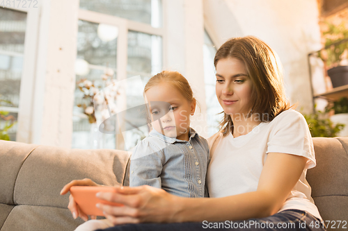 Image of Family time. Mother and daughter having time together at home, look happy and sincere