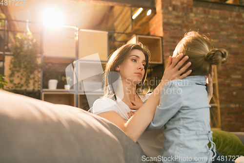 Image of Family time. Mother and daughter having time together at home, look happy and sincere