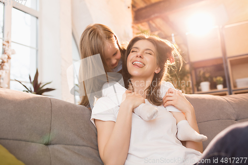 Image of Family time. Mother and daughter having time together at home, look happy and sincere