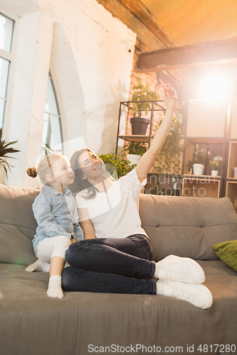 Image of Family time. Mother and daughter having time together at home, look happy and sincere