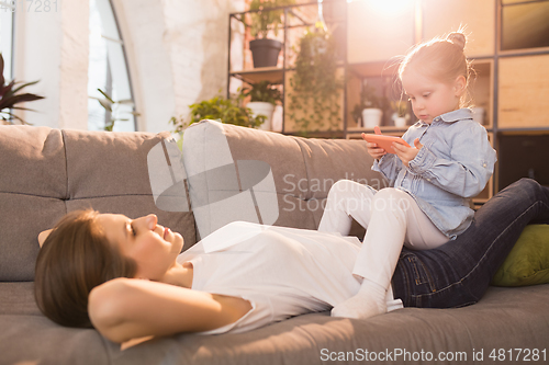 Image of Family time. Mother and daughter having time together at home, look happy and sincere