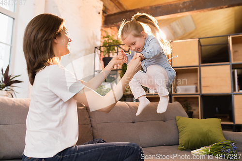 Image of Family time. Mother and daughter having time together at home, look happy and sincere