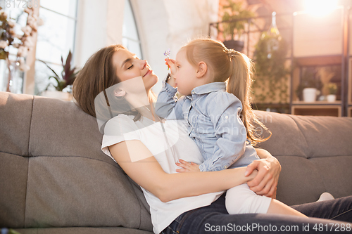 Image of Family time. Mother and daughter having time together at home, look happy and sincere