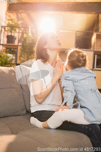 Image of Family time. Mother and daughter having time together at home, look happy and sincere