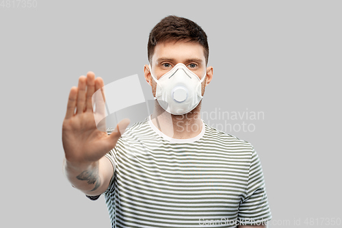 Image of man in respirator mask making stop gesture