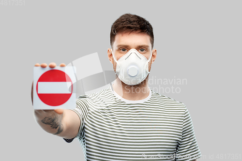 Image of man in respirator mask showing stop sign