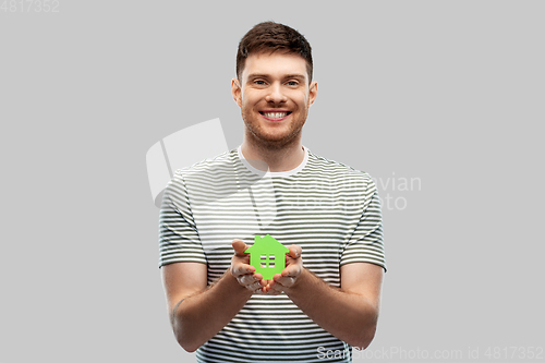 Image of smiling young man holding green house icon