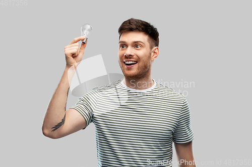 Image of smiling young man holding lighting bulb