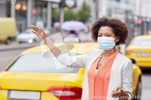 Image of african woman in face mask catching taxi in city