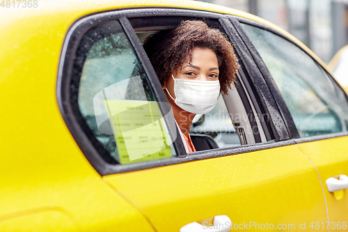 Image of african american woman wearing face mask in taxi