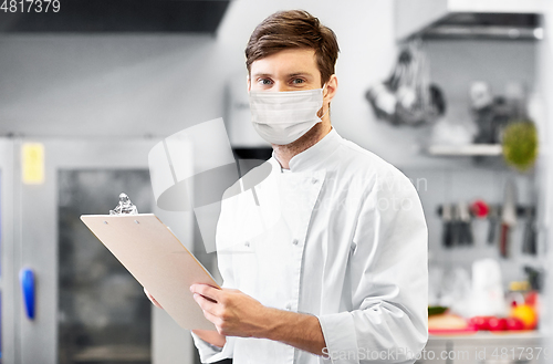 Image of chef with clipboard in face mask at restaurant