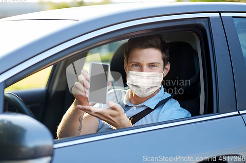 Image of male car driver with smartphone wearing face mask