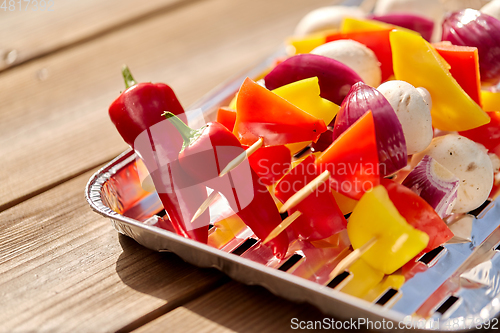 Image of close up of vegetables on skewers on foil grill